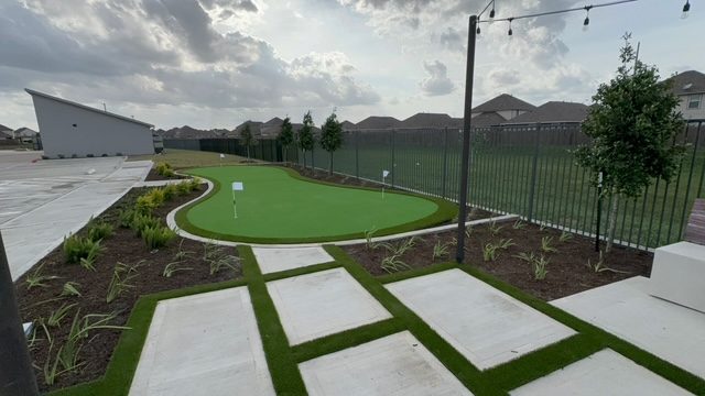 Backyard putting green with paver walkway and string lights