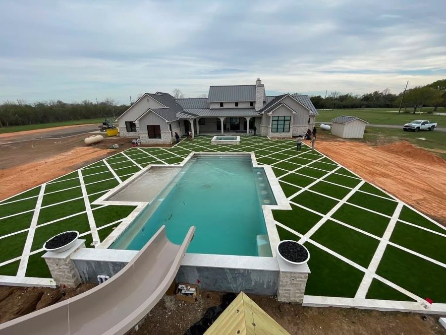 Custom diamond-pattern turf and paver patio surrounding a pool, spa, and waterslide at a large estate home