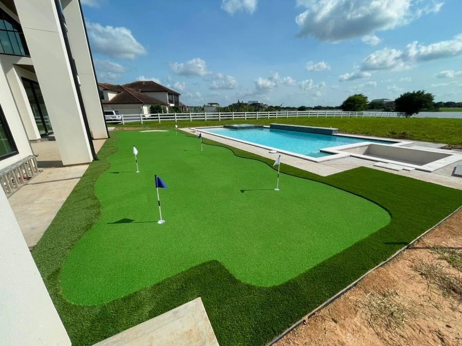 Multi-hole backyard putting green next to a pool at a modern home