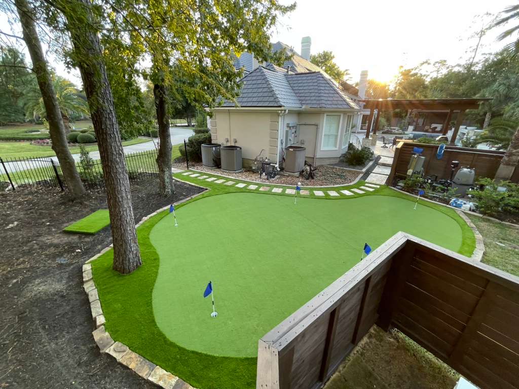 Estate backyard putting green with multiple holes at golden hour